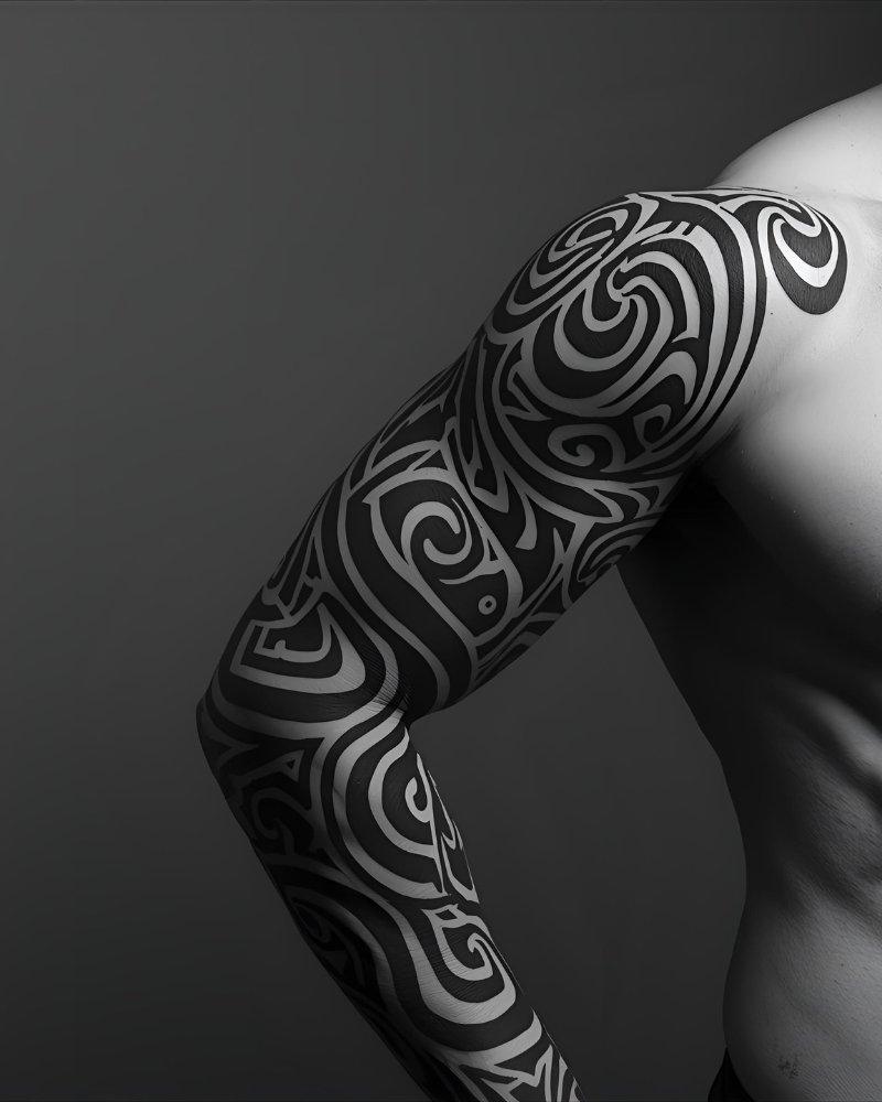 Tatuagem masculina no braço, estilo maori, cobrindo o braço inteiro.