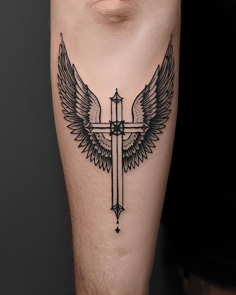 Tatuagem masculina no braço de cruz com asas.