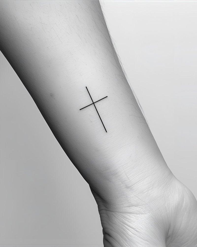 Tatuagem pequena masculina com significado de cruz, simbolizando fé.